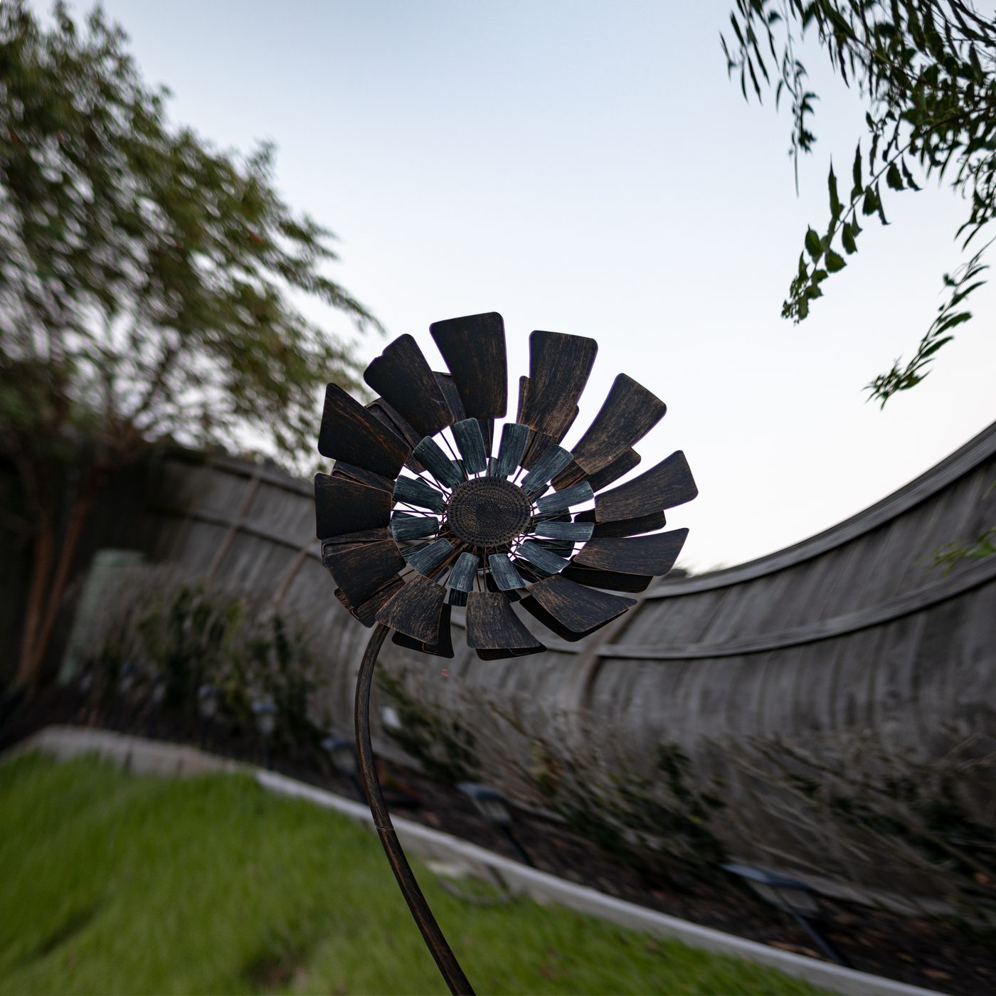 Whirlwinds — cover art: a metal wind spinner in a garden